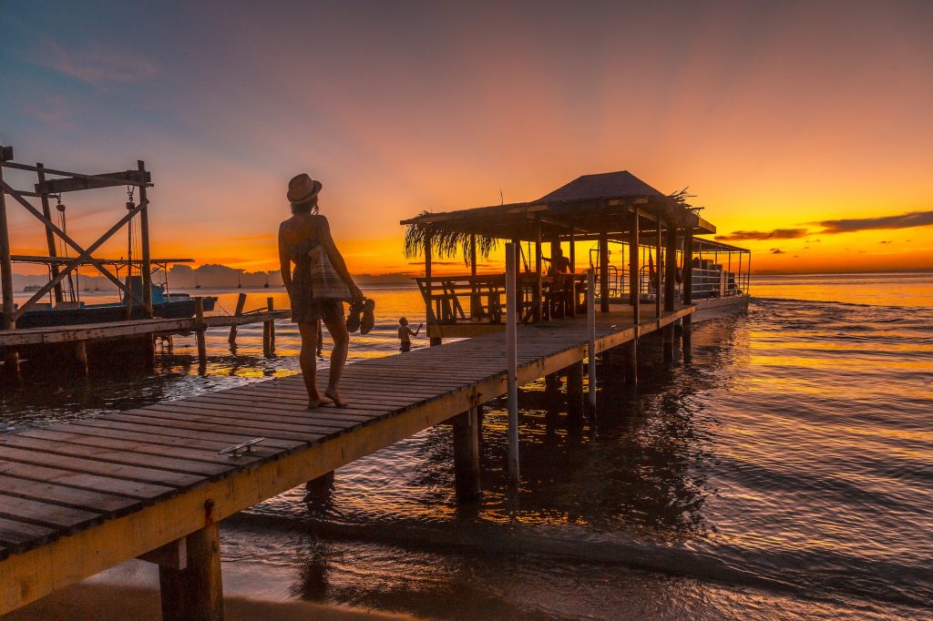 A young girl in a sunset on a pier on a beach on Roatan Island. Honduras